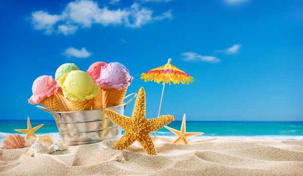 Ice creams cones and seashells in the sand on the beach with ocean landscape