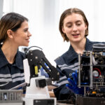 Engineer woman working on AI technology in robotics and electronics engineering laboratory. University students' research project is programming robot machine with intelligent mechanical control